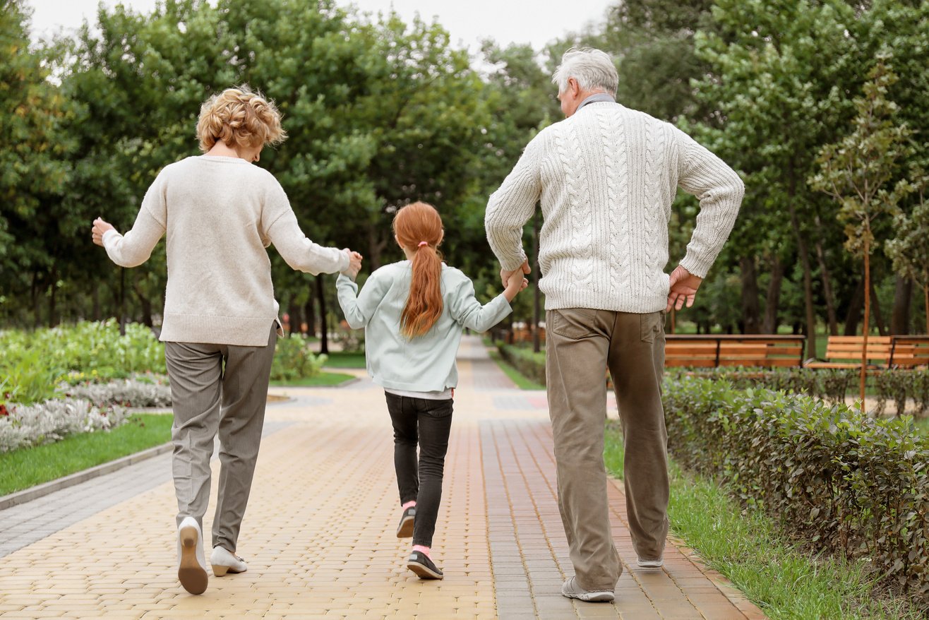 Little Girl with Grandparents Walking in Park